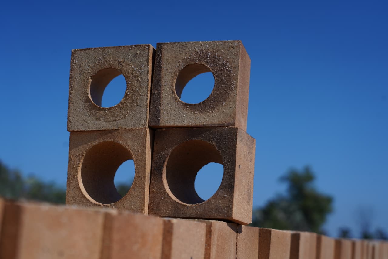 Four refractory bricks with round holes against blue sky
